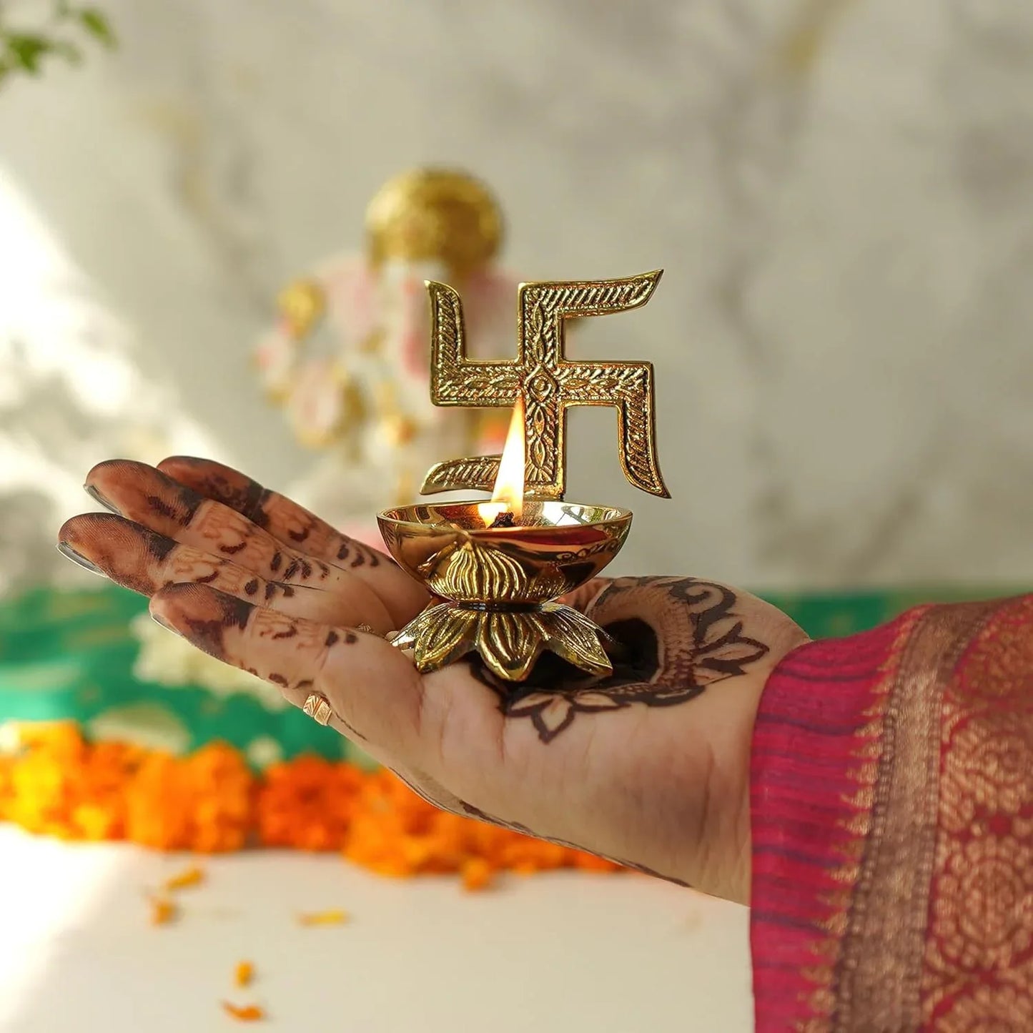 Hand holding a gold-colored oil lamp with a swastika symbol