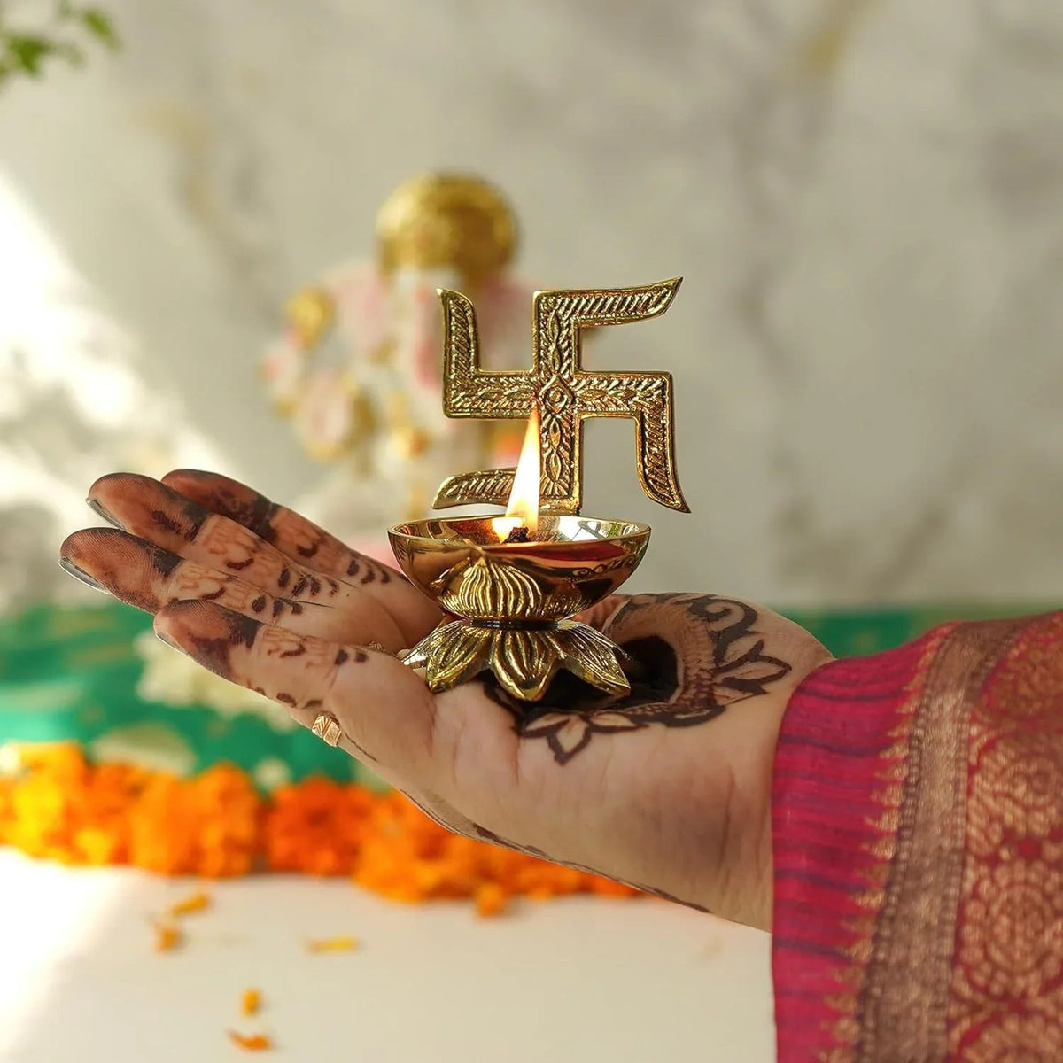Hand holding a gold-colored oil lamp with a swastika symbol
