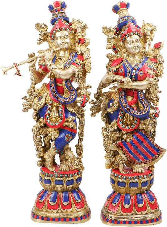 Monumental 29-inch solid brass Radha Krishna idol pair — vibrant coral red and lapis blue stone inlay garments with gold scrollwork, flute-playing Krishna and standing Radha on stone-inlaid lotus bases — ArtyCraftz