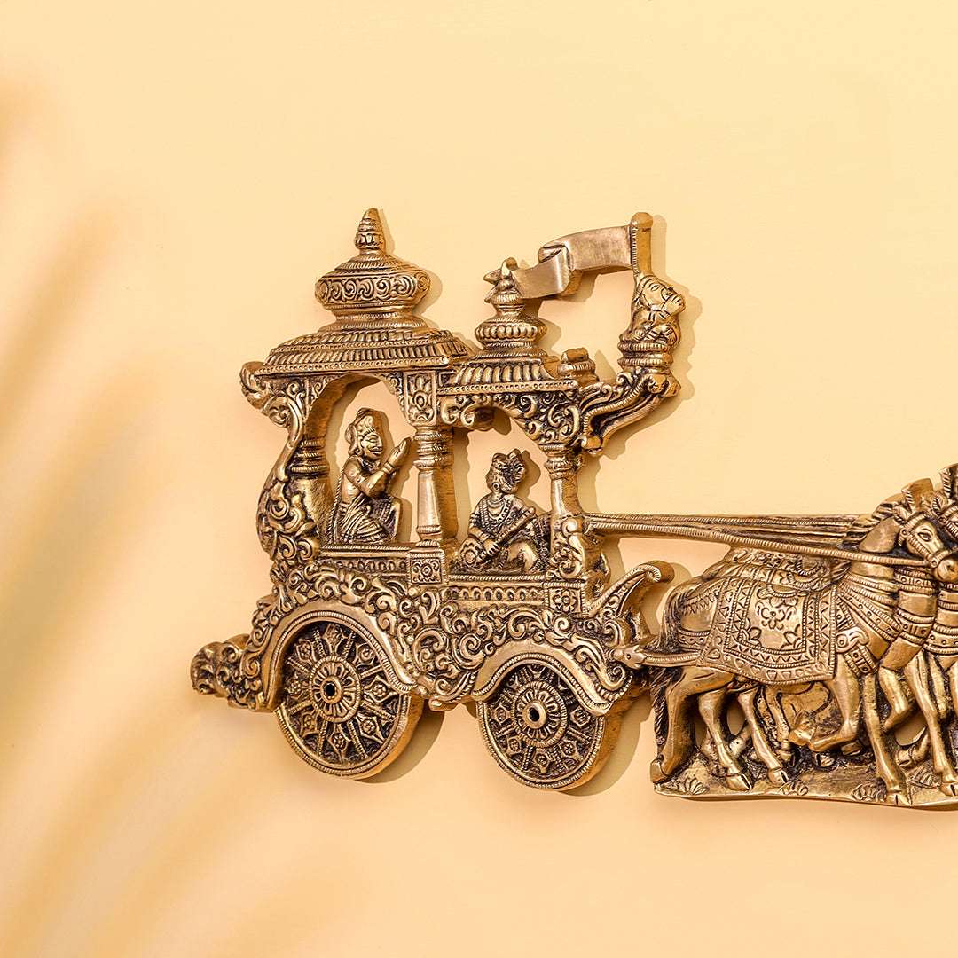 Decorative brass sculpture of an horse pulling a chariot with figures on a beige background