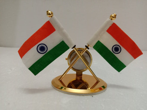 A small gold-colored tabletop display featuring two miniature Indian flags crossed over a round gold base on a white surface.