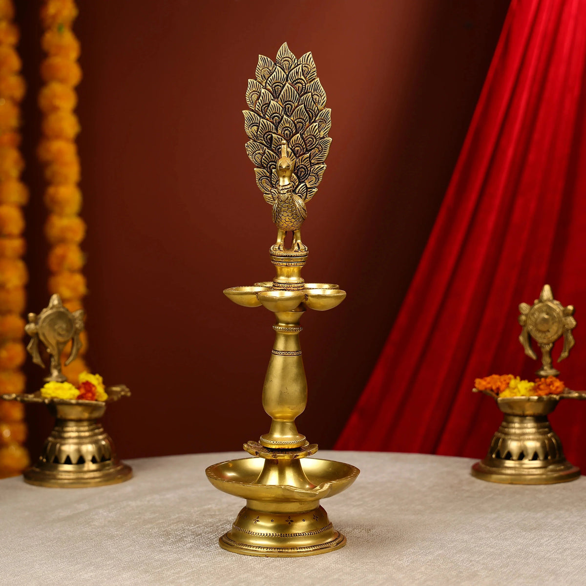 Decorative brass lamp with intricate design against a red curtain background