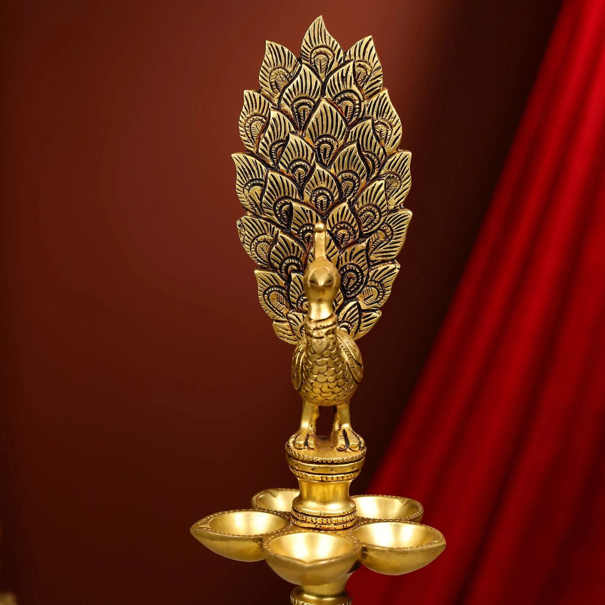 Decorative gold oil lamp with intricate design against a red curtain background