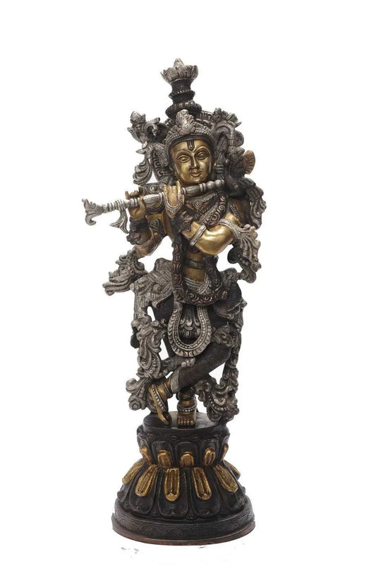 Handcrafted 20-inch solid brass Krishna idol in Tribhanga flute-playing pose — dramatic three-tone black, silver and gold finish with dense scrollwork garment, on dark lotus base — ArtyCraftz