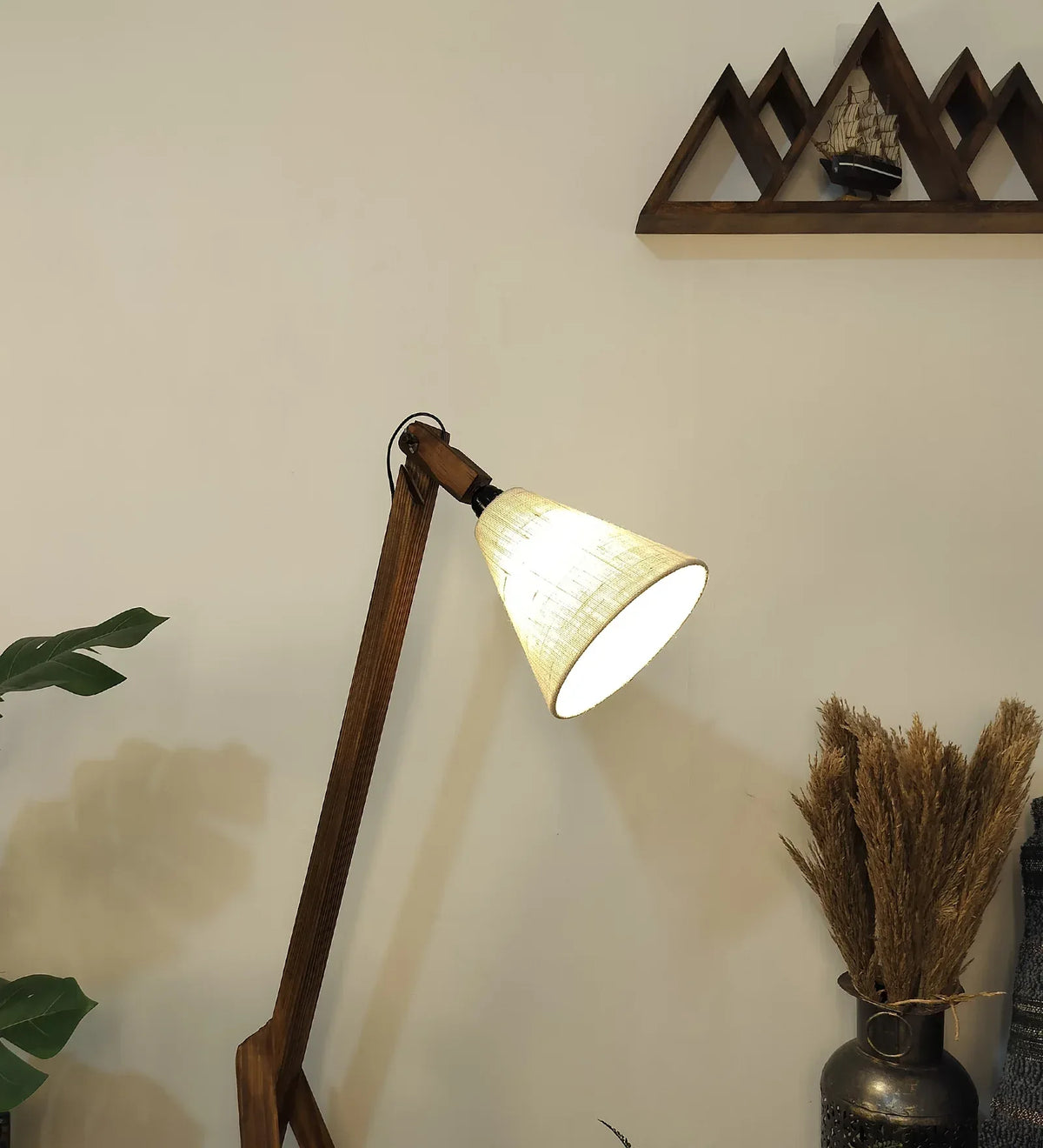 Wooden floor lamp with a light bulb on a neutral wall.
