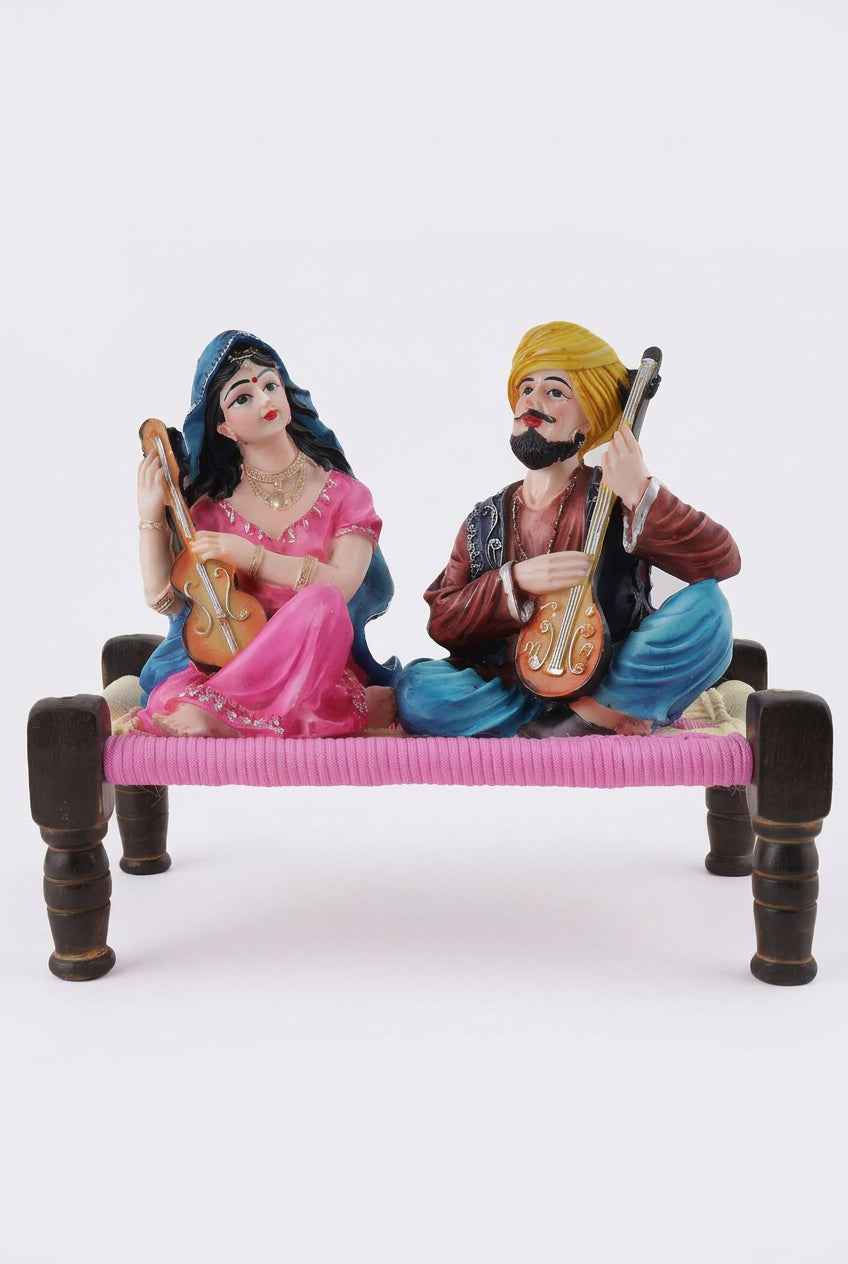 Multicolour resin Rajasthani musical couple figurine playing string instruments while seated on a traditional miniature charpai-artycraftz.com