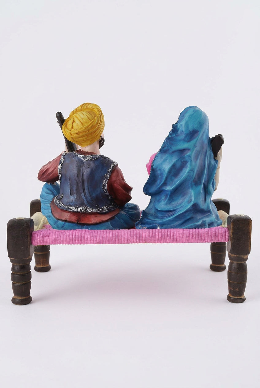 Multicolour resin Rajasthani musical couple figurine playing string instruments while seated on a traditional miniature charpai-artycraftz.com