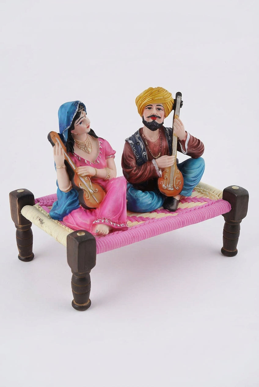 Multicolour resin Rajasthani musical couple figurine playing string instruments while seated on a traditional miniature charpai-artycraftz.com