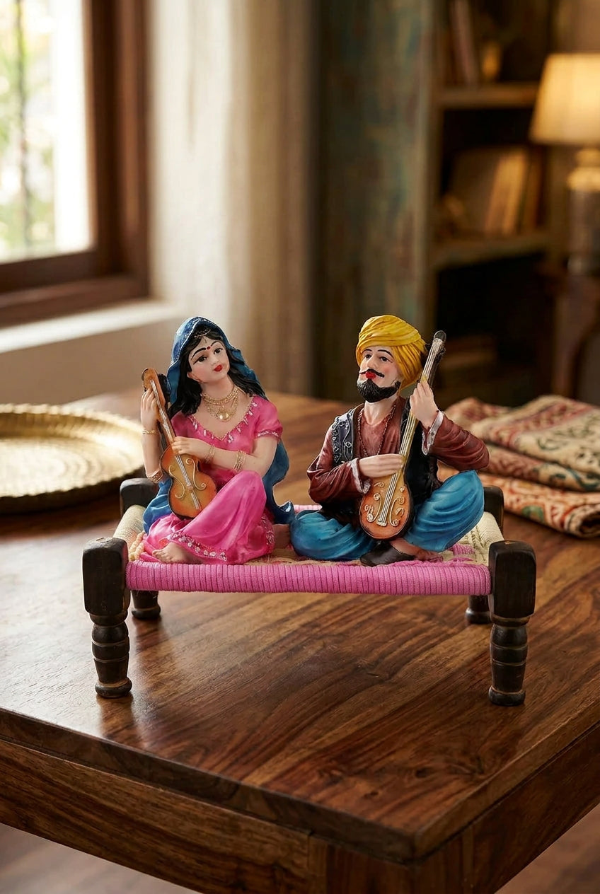 Multicolour resin Rajasthani musical couple figurine playing string instruments while seated on a traditional miniature charpai-artycraftz.com