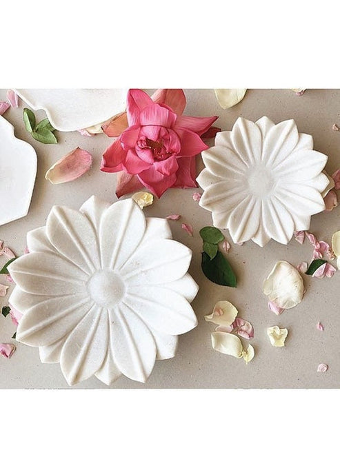 White ceramic flower-shaped dishes with a pink flower and petals on a light background