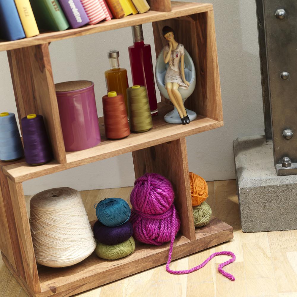 Wooden shelf with colorful yarn and bottles on a wooden floor
