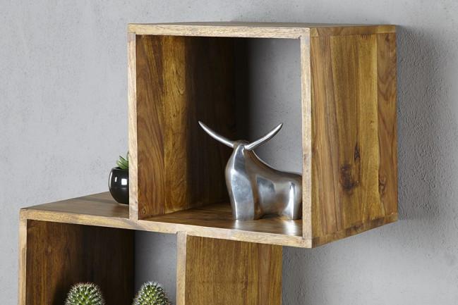 Wooden shelf with a metallic sculpture and small plant against a gray wall
