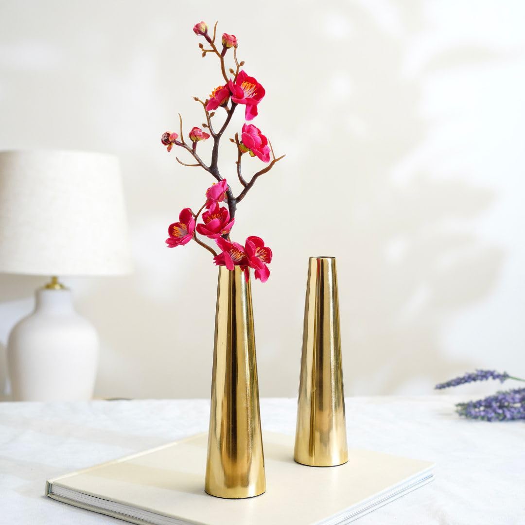 Two gold vases with pink flowers on a white surface.