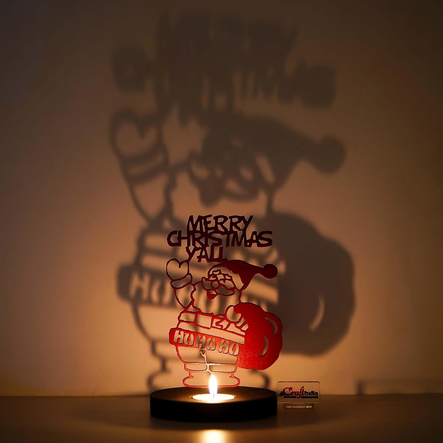 Decorative lamp with Santa Claus design and 'Merry Christmas Y'all' text, casting a shadow on a wall.