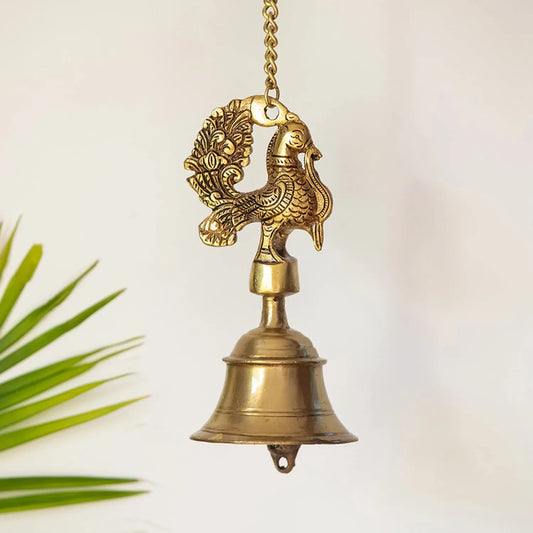 Brass bell with peacock design on a white background