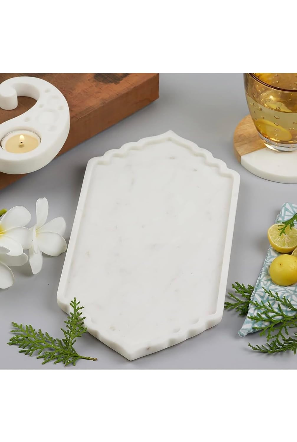 White decorative tray on a table with candles, lemons, and flowers.