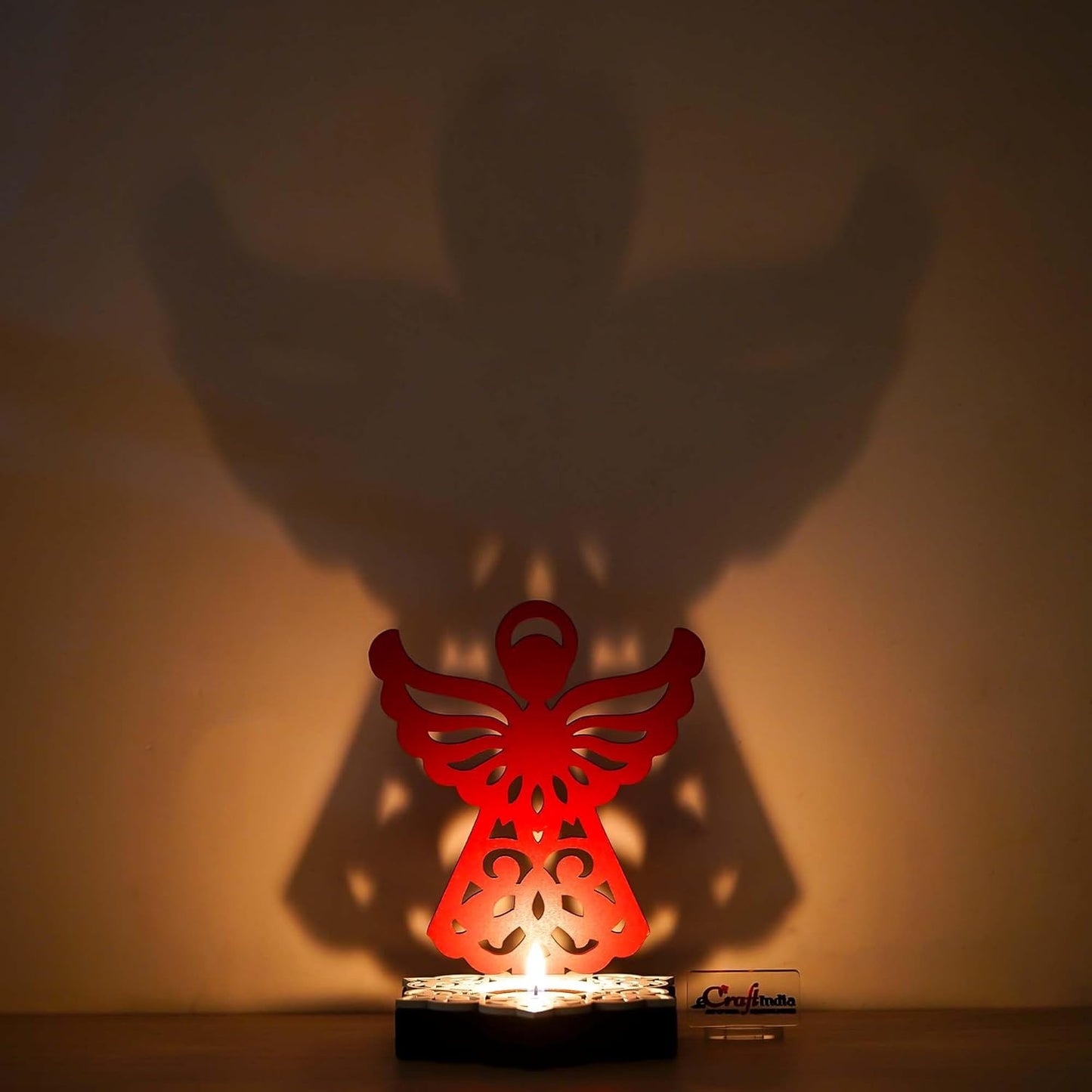 Red angel-shaped lamp casting a shadow on a wall