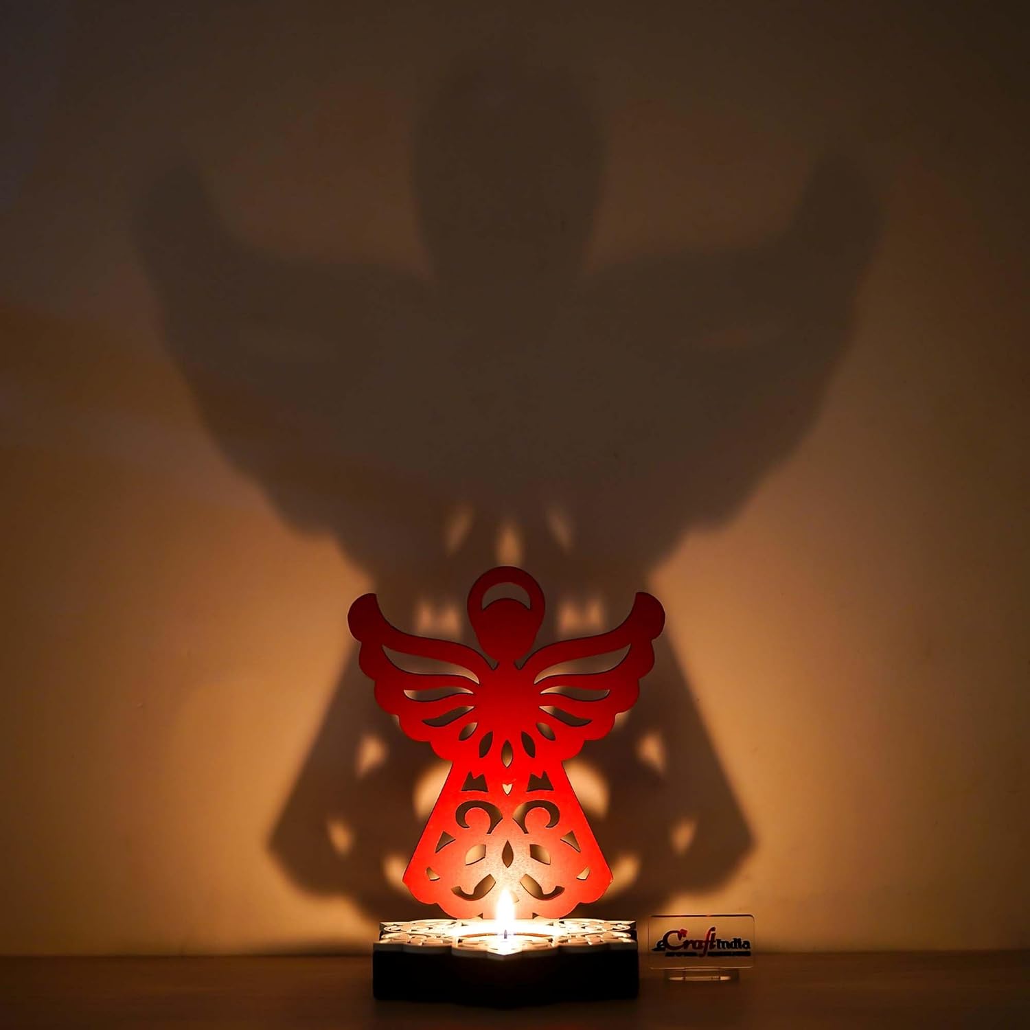 Red angel-shaped lamp casting a shadow on a wall
