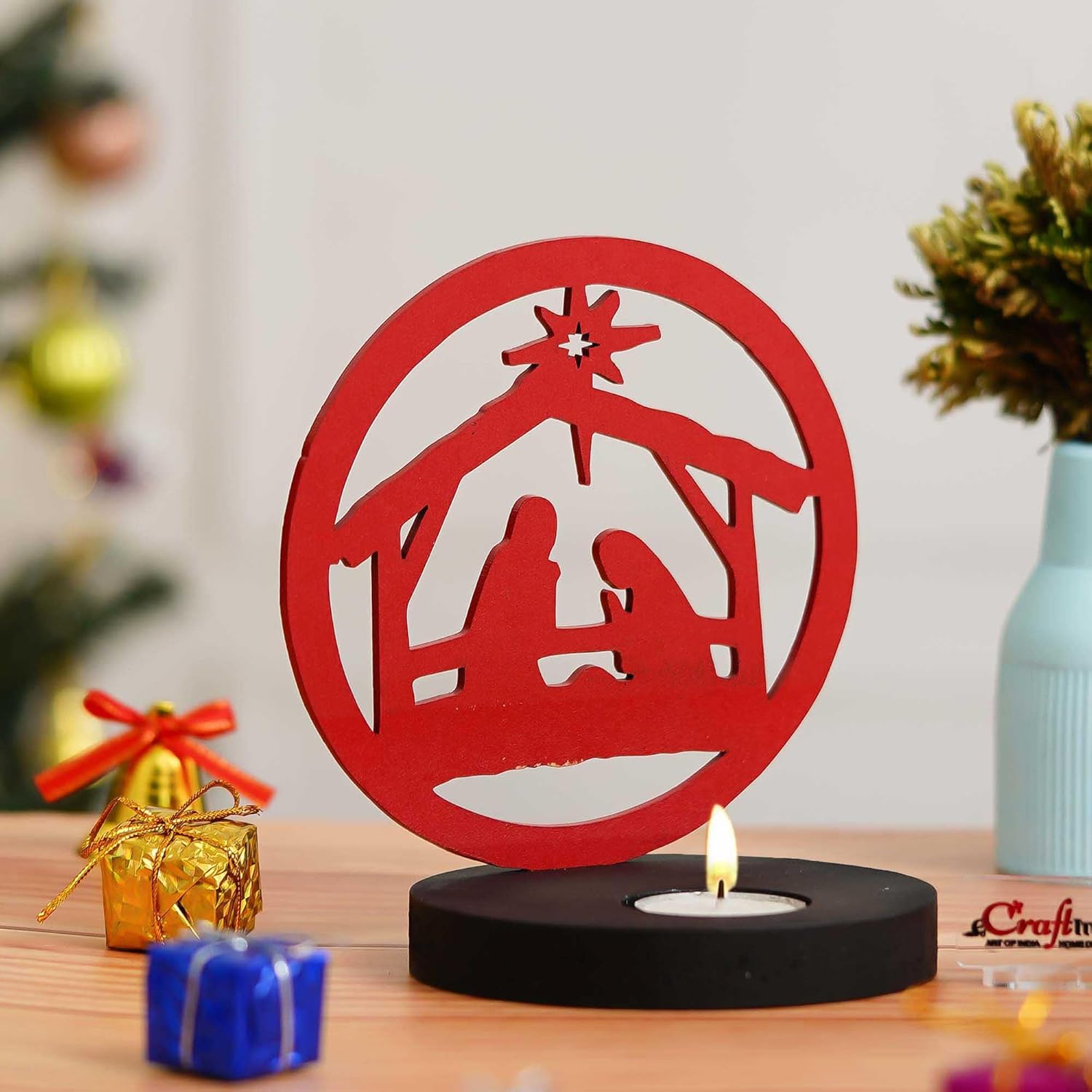 Red nativity scene cutout with a candle on a wooden surface
