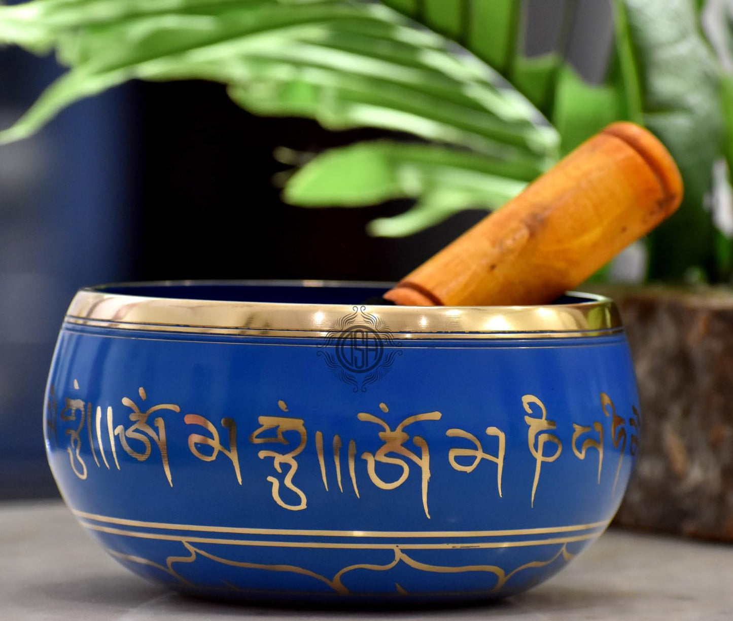Blue singing bowl with gold text and a wooden stick