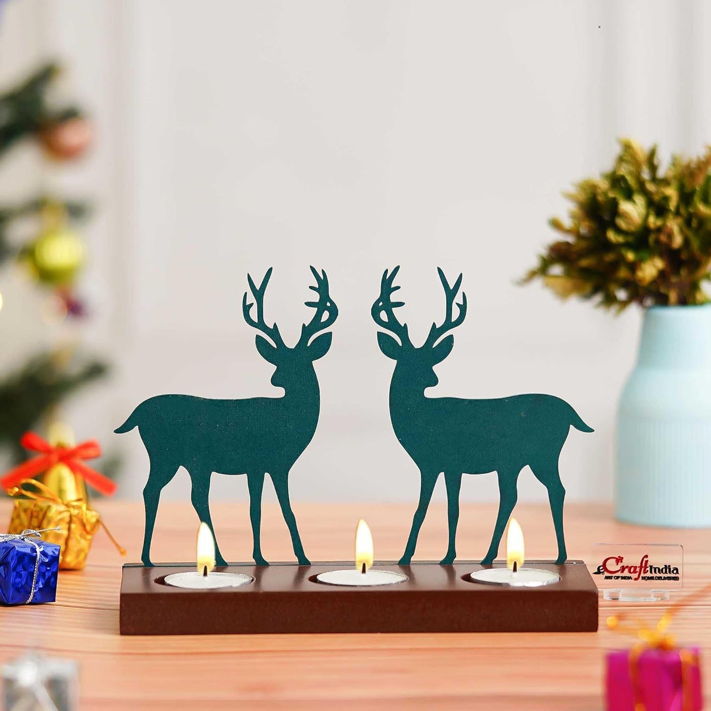 Decorative teal deer candle holder on a wooden base with candles, placed on a table with festive decorations.