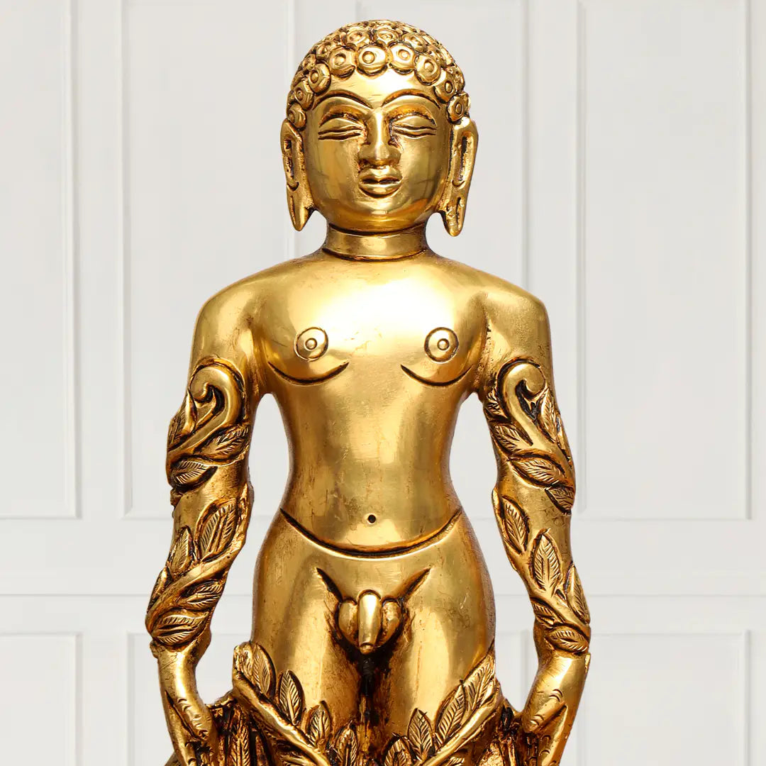 A golden Buddha statue with a stylized, semi-nude human form, featuring detailed leaf patterns on the arms and a serene face, set against a white paneled background.