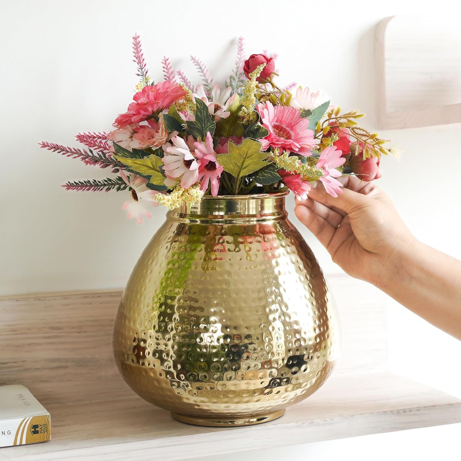 Gold vase with flowers being held by a hand