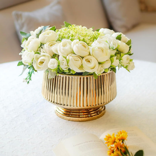 Gold vase with white flowers on a white surface