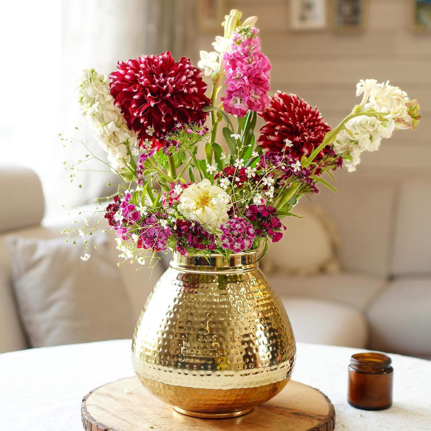Gold vase with colorful flowers on a table in a living room setting