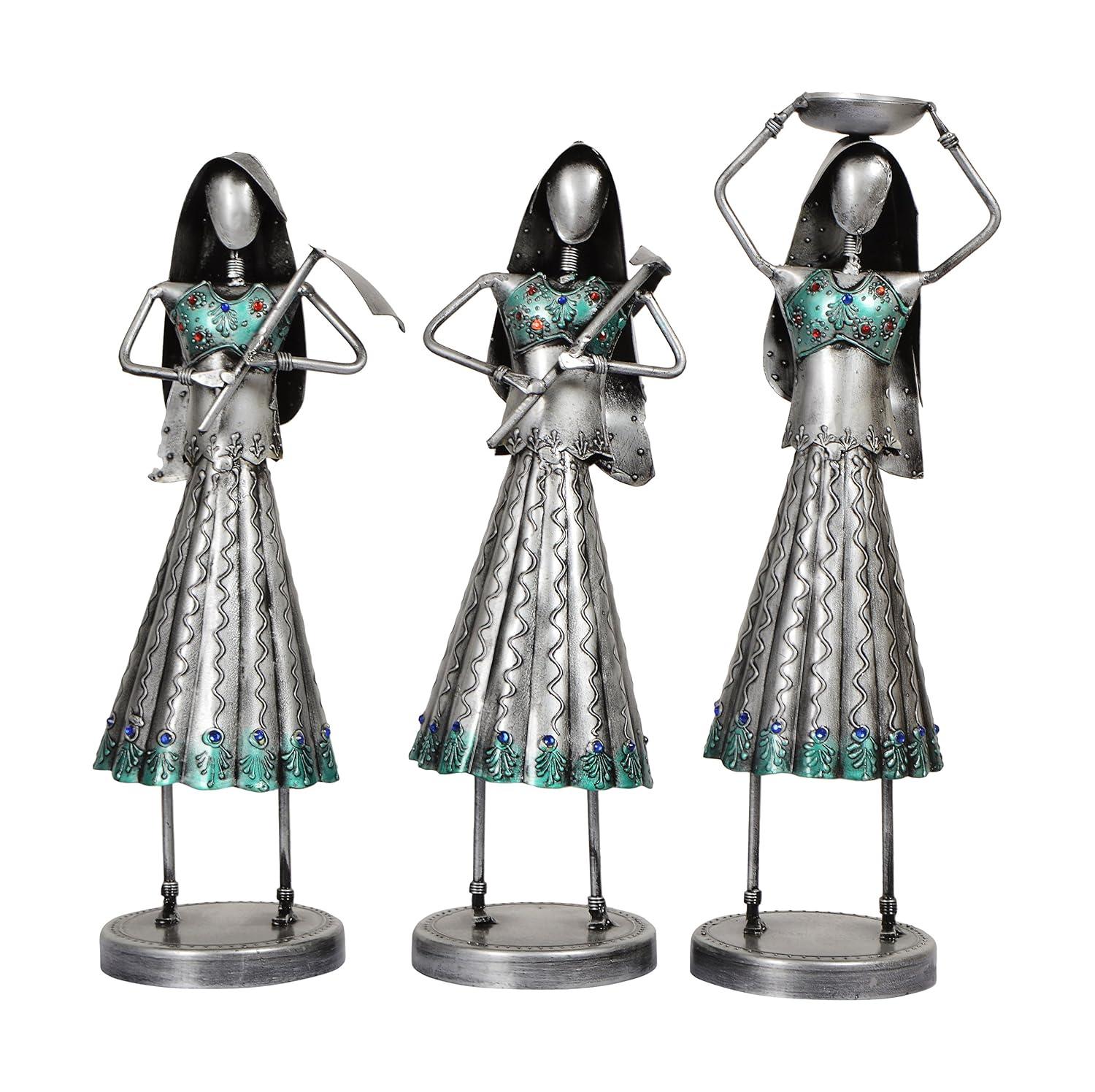 Three metallic figurines with decorative dresses on a white background