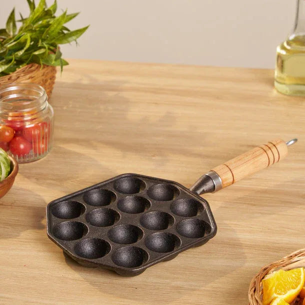Black cast iron pan with wooden handle on a wooden table