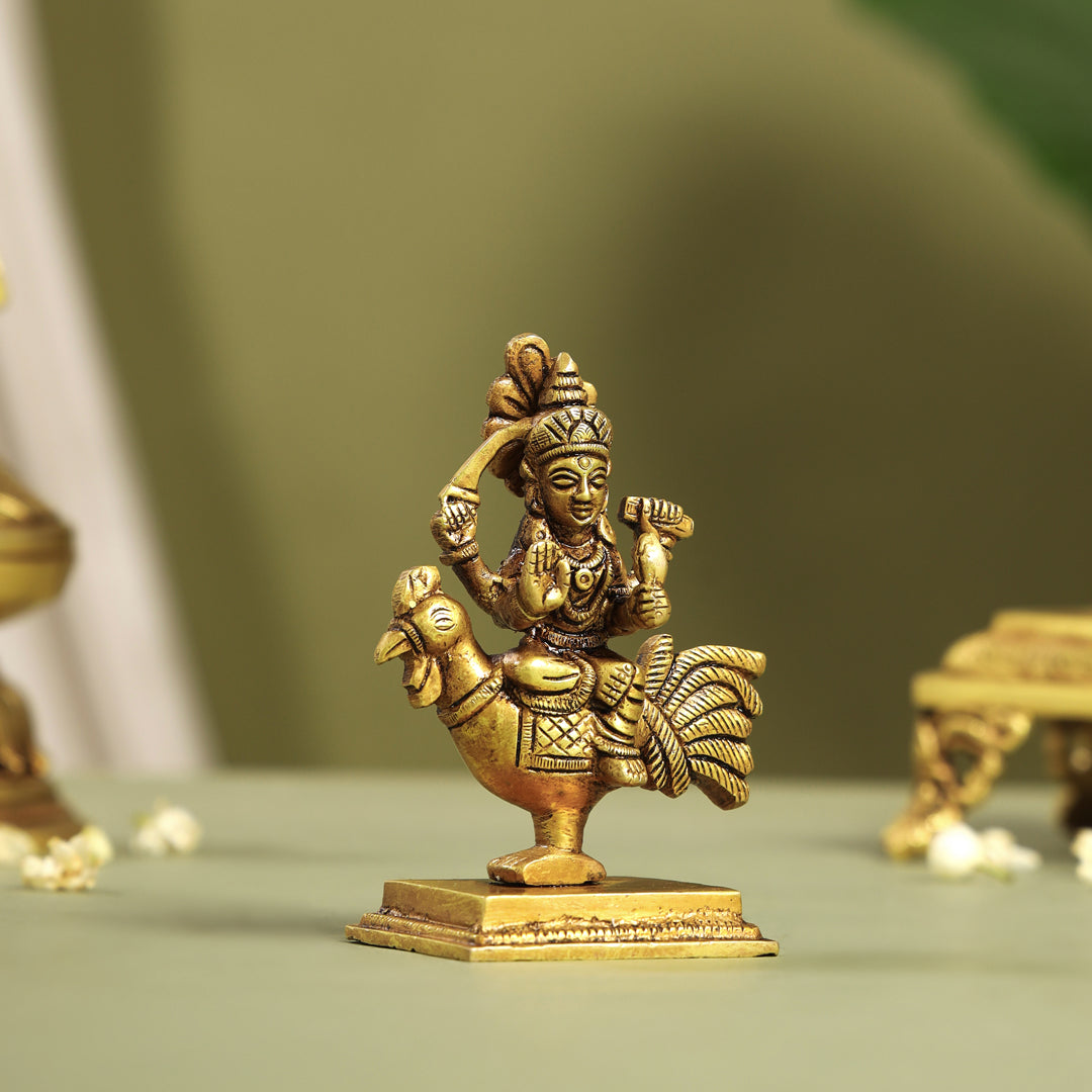 Bronze statue of parvathi on a rooster's back with a blurred green background