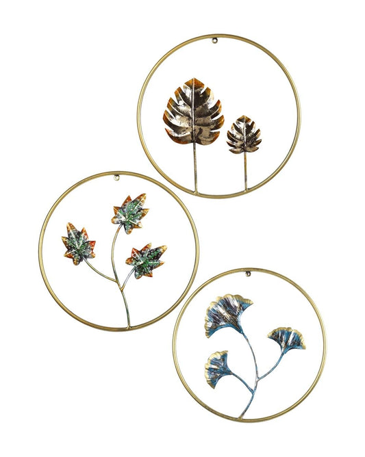 Three circular metal wall art pieces with leaf designs on a white background