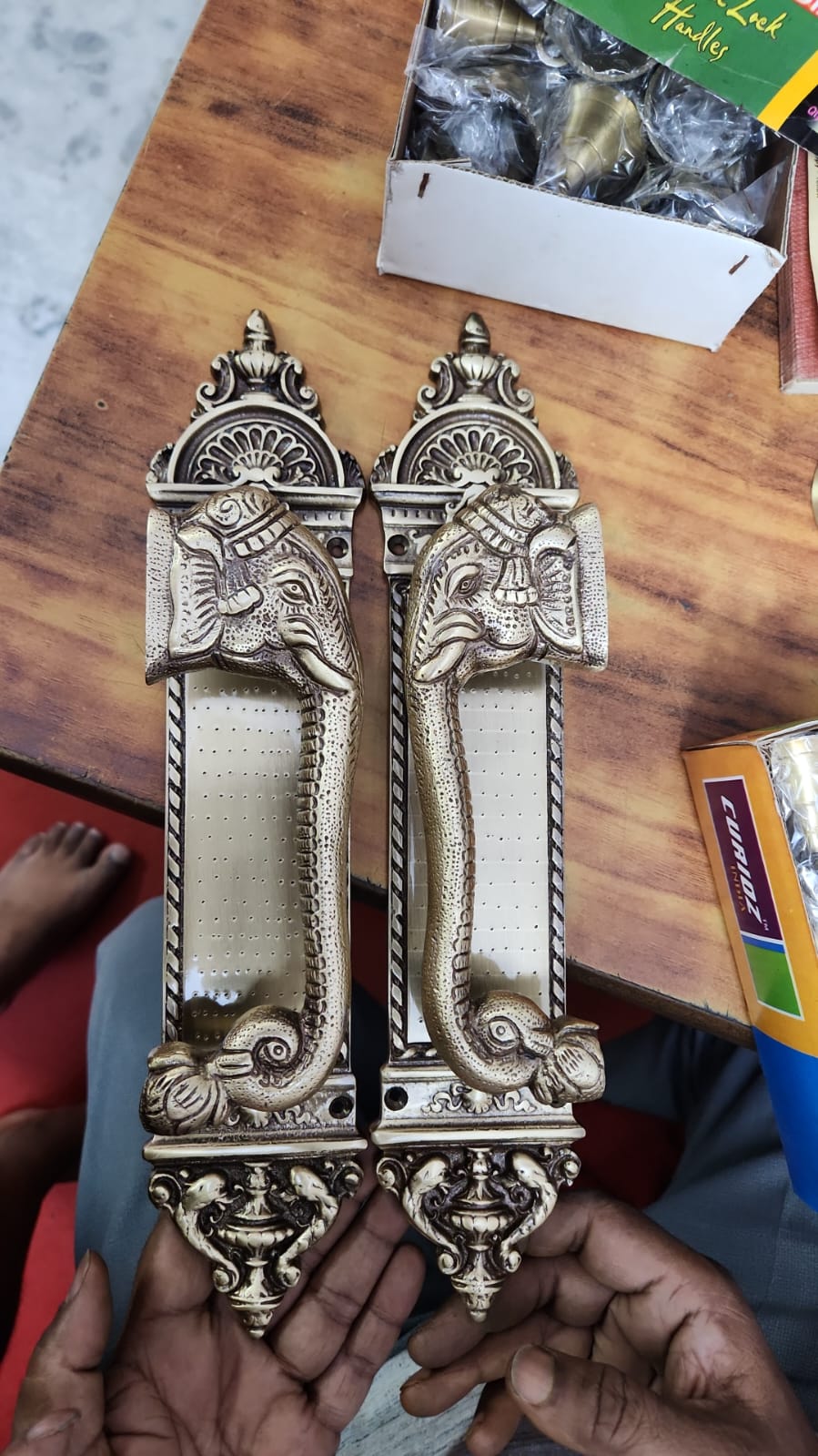 Decorative door handles on a wooden surface with a box of matches in the background.