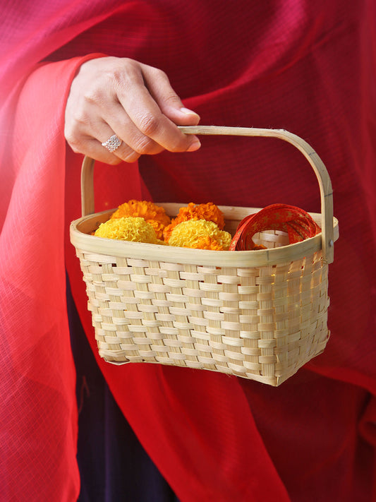 Person holding a woven basket with marigold flowers and red items