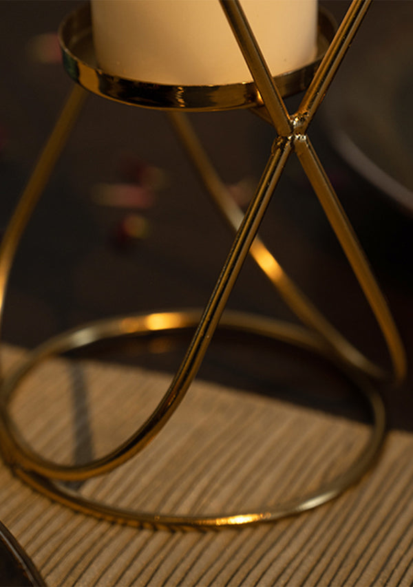 Gold candle holder with a white candle on a textured surface