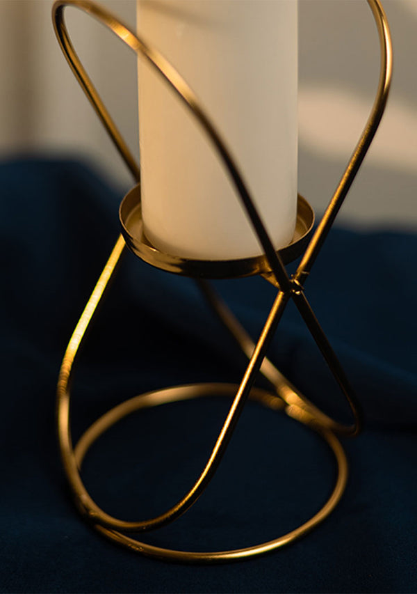 Gold candle holder with a white candle on a dark blue background