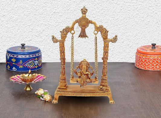 Handcrafted 12.5-inch solid brass Ganesha on swing Jhula idol — South Indian temple style with elephant pillar capitals, Ganesha arch finial, brass chain suspension, Mooshika at base — ArtyCraftz