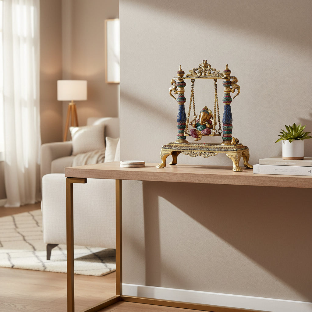 Handcrafted 13.2-inch brass Ganesha on swing jhula idol — stone-studded pillars in blue, pink and green, gold chain swing, decorative arch crown and lion-paw footed base — ArtyCraftz