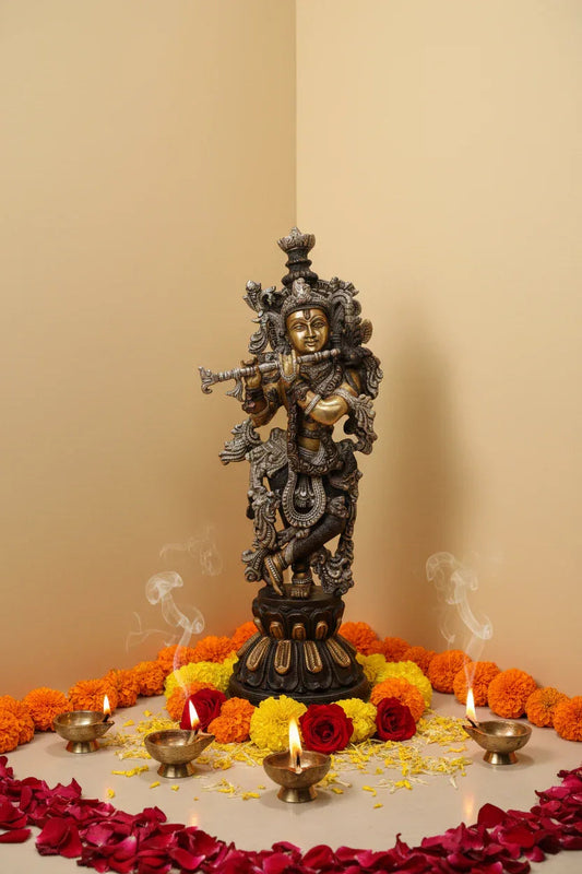 Handcrafted 20-inch solid brass Krishna idol in Tribhanga flute-playing pose — dramatic three-tone black, silver and gold finish with dense scrollwork garment, on dark lotus base — ArtyCraftz