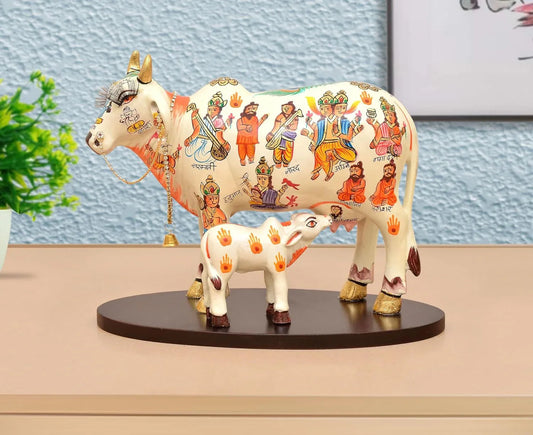 Handcrafted 8-inch resin Kamdhenu cow with calf — hand-painted multicolour with Hindu deities and saints including Hanuman, Narad, Saraswati and sages, gold hooves and brass bell chain — ArtyCraftz