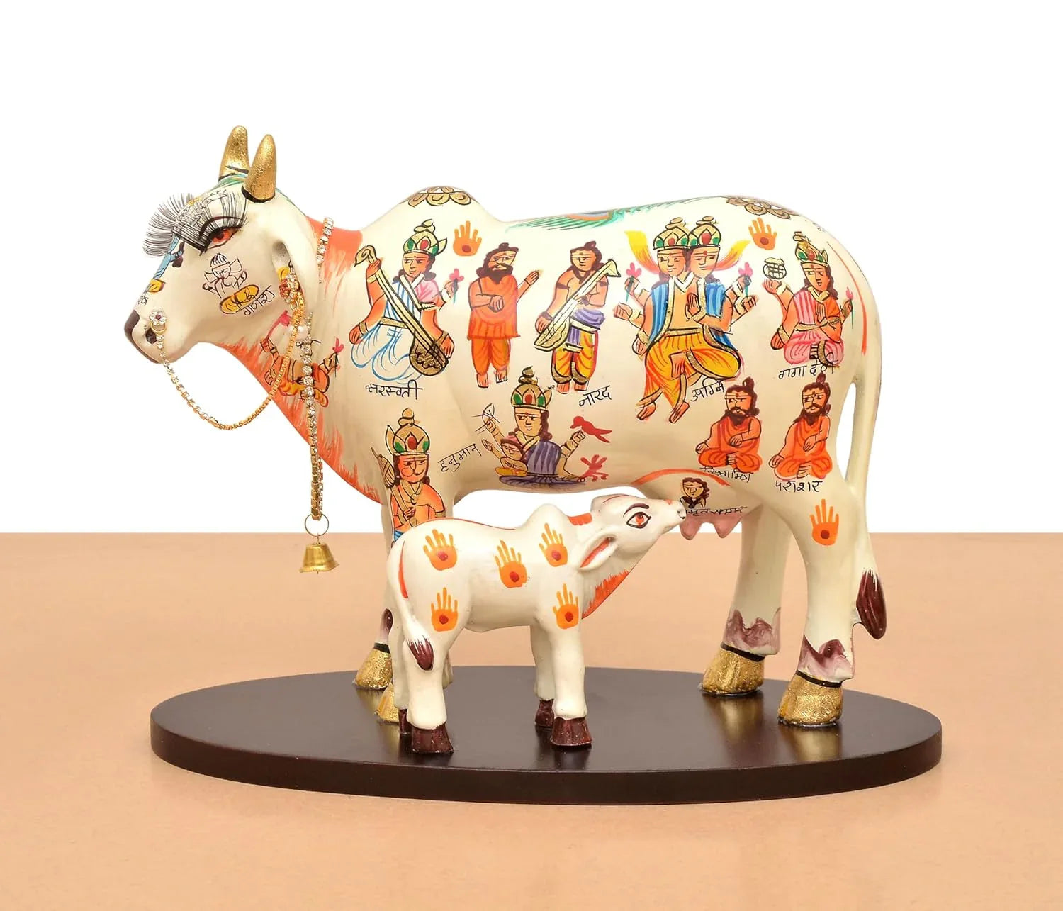 Handcrafted 8-inch resin Kamdhenu cow with calf — hand-painted multicolour with Hindu deities and saints including Hanuman, Narad, Saraswati and sages, gold hooves and brass bell chain — ArtyCraftz