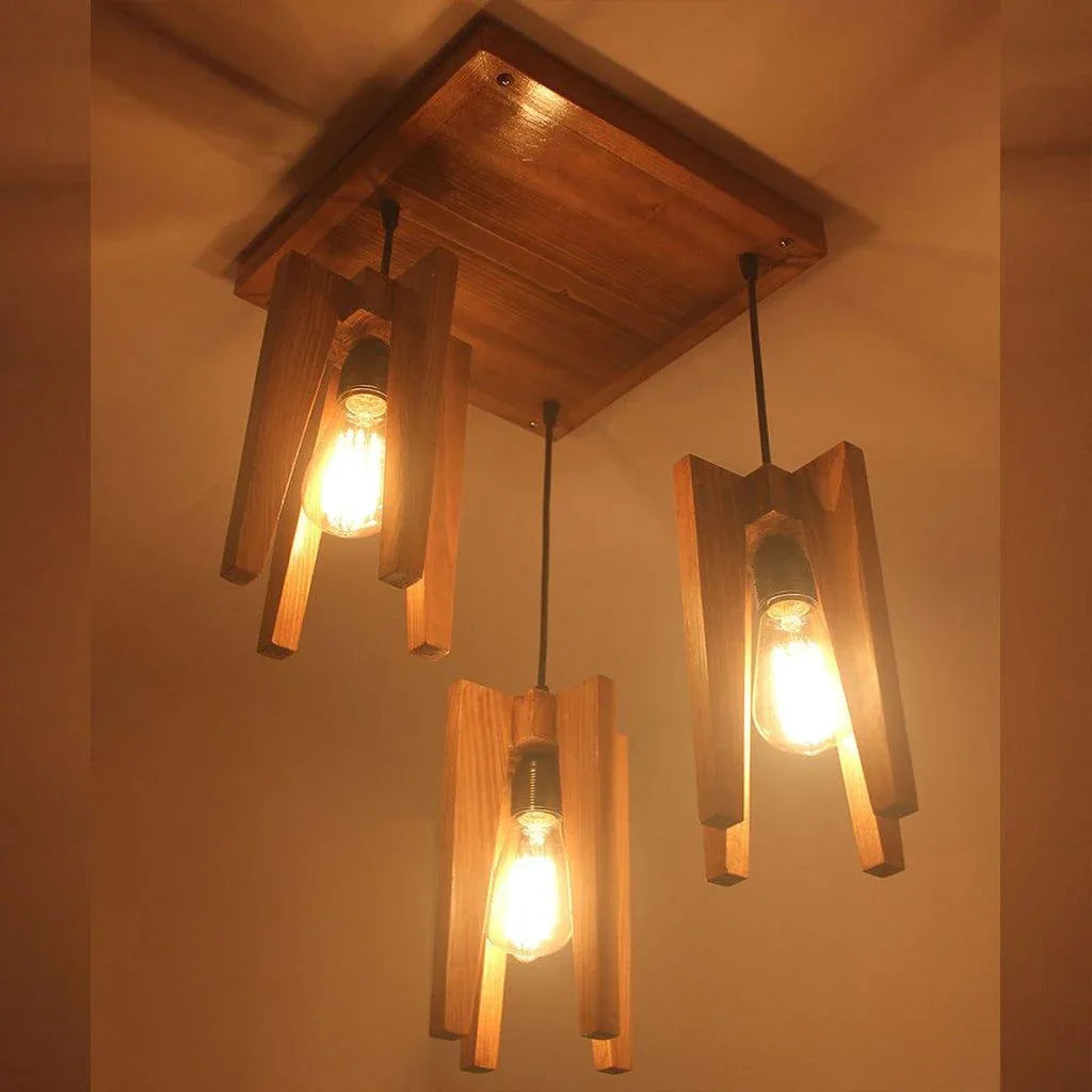 Wooden pendant light fixture with three lit bulbs against a plain wall.