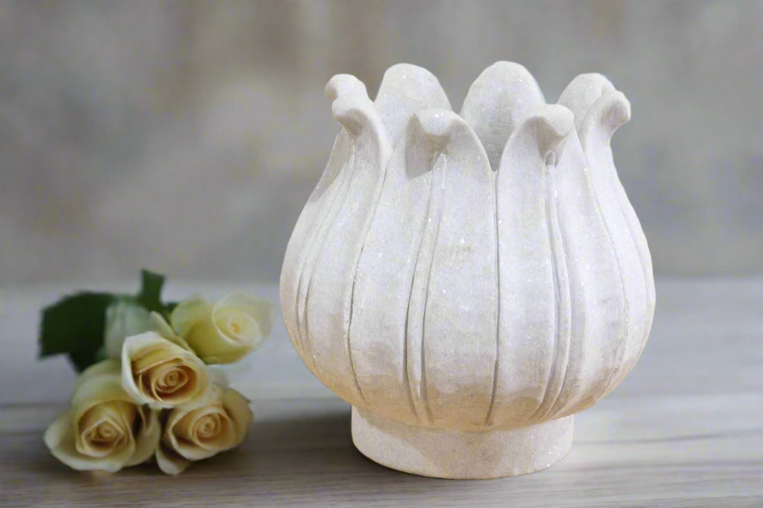 Decorative white vase with bird-like designs on a blurred background