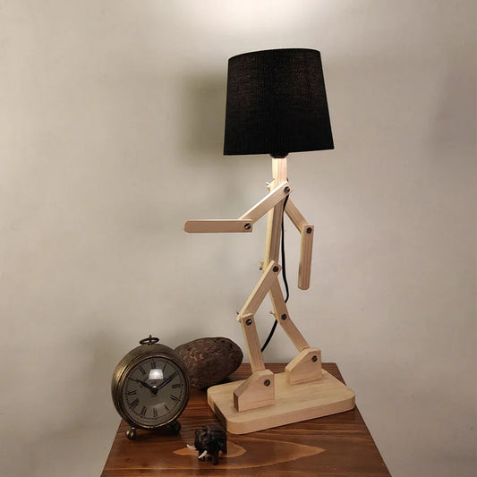 Wooden lamp with black shade on a wooden table against a beige wall