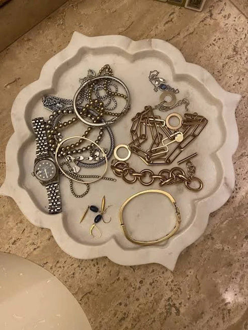 Collection of jewelry on a decorative white tray on a stone surface