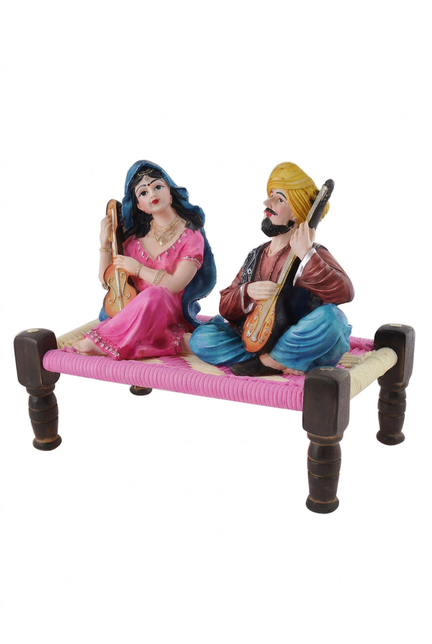 Multicolour resin Rajasthani musical couple figurine playing string instruments while seated on a traditional miniature charpai-artycraftz.com