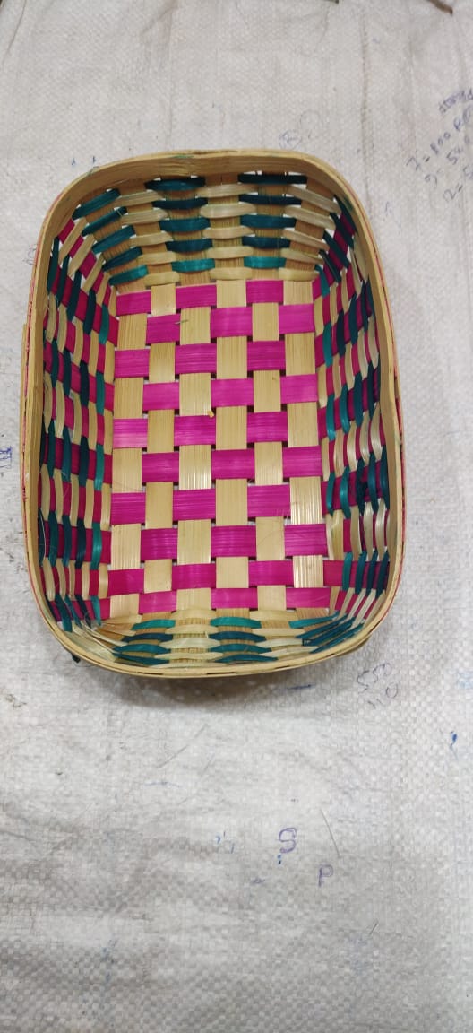 Woven basket with pink and green pattern on a textured surface