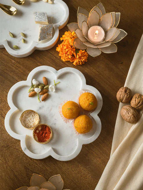 Decorative marble tray with oranges, nuts, and flowers on a wooden surface.