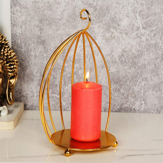 Red candle in a gold metal cage on a gray surface with a Buddha statue in the background